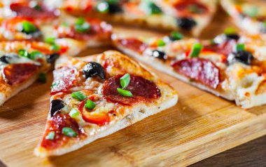 Pizza Mozzarella peyniri, sucuk, domates, biber, zeytin, salam. Ahşap masa arka plan üzerinde İtalyan pizza