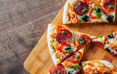 Pizza Mozzarella peyniri, sucuk, domates, biber, zeytin, salam. Ahşap masa arka plan üzerinde İtalyan pizza