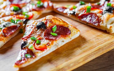 Pizza Mozzarella peyniri, sucuk, domates, biber, zeytin, salam. Ahşap masa arka plan üzerinde İtalyan pizza