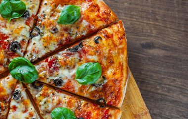 dilimlenmiş Pizza Mozzarella peyniri, domates, biber, zeytin, baharat ve taze fesleğen. İtalyan pizza. Pizza Margherita veya ahşap masa arka plan üzerinde Margarita