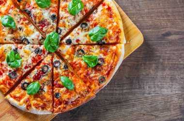 dilimlenmiş Pizza Mozzarella peyniri, domates, biber, zeytin, baharat ve taze fesleğen. İtalyan pizza. Pizza Margherita veya ahşap masa arka plan üzerinde Margarita