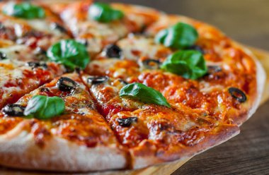 dilimlenmiş Pizza Mozzarella peyniri, domates, biber, zeytin, baharat ve taze fesleğen. İtalyan pizza. Pizza Margherita veya ahşap masa arka plan üzerinde Margarita