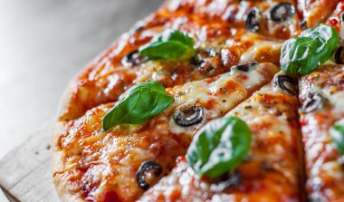 dilimlenmiş Pizza Mozzarella peyniri, domates, biber, zeytin, baharat ve taze fesleğen. İtalyan pizza. Pizza Margherita veya ahşap masa arka plan üzerinde Margarita