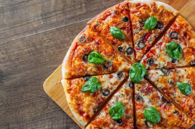 dilimlenmiş Pizza Mozzarella peyniri, domates, biber, zeytin, baharat ve taze fesleğen. İtalyan pizza. Pizza Margherita veya ahşap masa arka plan üzerinde Margarita