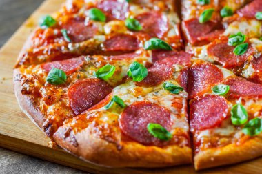 Pepperoni Pizza Mozzarella peyniri, salam, domates, biber, baharat ve taze fesleğen. Ahşap masa arka plan üzerinde İtalyan pizza