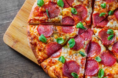 Pepperoni Pizza Mozzarella peyniri, salam, domates, biber, baharat ve taze fesleğen. Ahşap masa arka plan üzerinde İtalyan pizza
