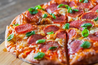 Pepperoni Pizza Mozzarella peyniri, salam, domates, biber, baharat ve taze fesleğen. Ahşap masa arka plan üzerinde İtalyan pizza