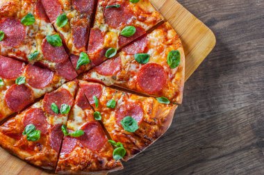 Pepperoni Pizza Mozzarella peyniri, salam, domates, biber, baharat ve taze fesleğen. Ahşap masa arka plan üzerinde İtalyan pizza