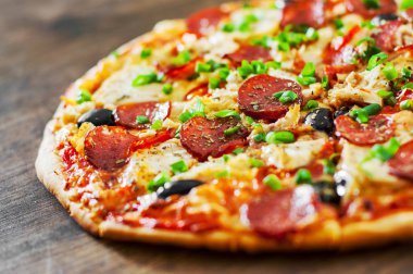 Tavuk eti, Mozzarella peyniri, sucuk, domates, zeytin, salam pizza. Ahşap arka plan üzerinde İtalyan pizza