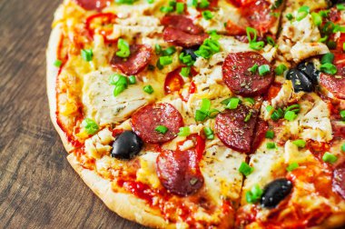 Tavuk eti, Mozzarella peyniri, sucuk, domates, zeytin, salam pizza. Ahşap arka plan üzerinde İtalyan pizza