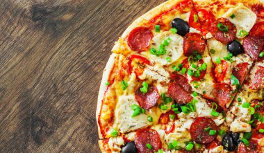 Tavuk eti, Mozzarella peyniri, sucuk, domates, zeytin, salam pizza. Ahşap arka plan üzerinde İtalyan pizza