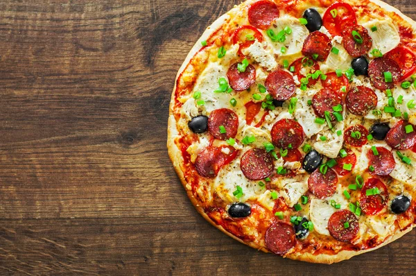 Tavuk eti, Mozzarella peyniri, sucuk, domates, zeytin, salam pizza. Ahşap arka plan üzerinde İtalyan pizza