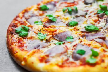 Pizza Mozzarella peyniri, jambon, biber, et, domates sosu, baharat ve taze fesleğen. Ahşap arka plan üzerinde İtalyan pizza