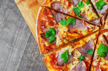 Pizza Mozzarella peyniri, jambon, biber, et, domates sosu, baharat ve taze fesleğen. Ahşap arka plan üzerinde İtalyan pizza
