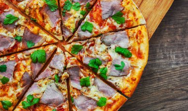 Pizza Mozzarella peyniri, jambon, biber, et, domates sosu, baharat ve taze fesleğen. Ahşap arka plan üzerinde İtalyan pizza