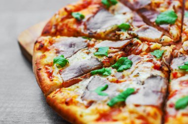 Pizza Mozzarella peyniri, jambon, biber, et, domates sosu, baharat ve taze fesleğen. Ahşap arka plan üzerinde İtalyan pizza