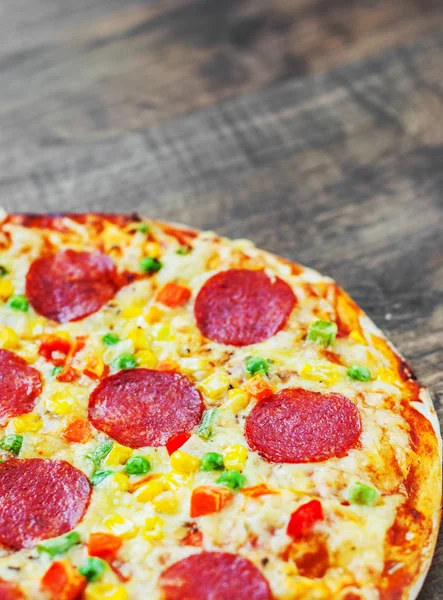 Pizza with vegetables mix, Mozzarella cheese, pepperoni, tomato, salami. Italian pizza on wooden table background
