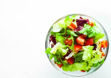Beyaz arka plan üzerinde izole cam kapta domates ile çeşitli taze karışımı salata yaprakları.