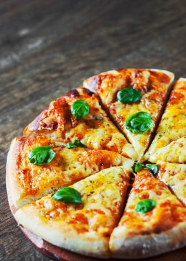 Pizza Mozzarella peyniri, domates, biber, baharat ve taze fesleğen. İtalyan pizza. Pizza Margherita veya ahşap masa arka plan üzerinde Margarita