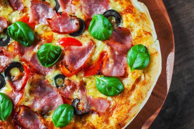 Pizza Mozzarella peyniri, jambon, biber, zeytin, et, domates sosu, baharat ve taze fesleğen. Ahşap arka plan üzerinde İtalyan pizza
