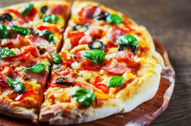 Pizza Mozzarella peyniri, jambon, biber, zeytin, et, domates sosu, baharat ve taze fesleğen. Ahşap arka plan üzerinde İtalyan pizza