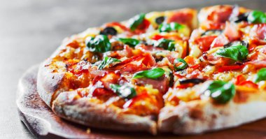 Pizza Mozzarella peyniri, jambon, biber, zeytin, et, domates sosu, baharat ve taze fesleğen. Ahşap arka plan üzerinde İtalyan pizza