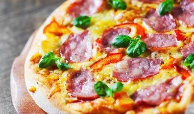 Pizza Mozzarella peyniri, jambon, biber, et, domates sosu, baharat ve taze fesleğen. İtalyan pizza üzerinde ahşap