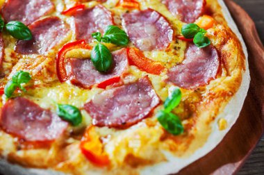 Pizza Mozzarella peyniri, jambon, biber, et, domates sosu, baharat ve taze fesleğen. İtalyan pizza üzerinde ahşap
