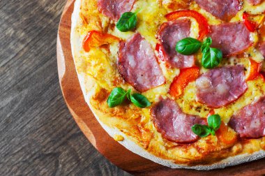 Pizza Mozzarella peyniri, jambon, biber, et, domates sosu, baharat ve taze fesleğen. İtalyan pizza üzerinde ahşap