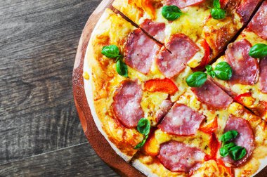 Pizza Mozzarella peyniri, jambon, biber, et, domates sosu, baharat ve taze fesleğen. İtalyan pizza üzerinde ahşap