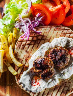 Baharatlı bifteki, frikadelle veya frikkadel Köfte kıyma ve Pide, tzatziki sos, sebze salatası ve patates kızartması ile kuzu ile. Yunan köfte keftedes veya Keftedakia.