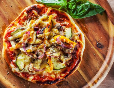 vejetaryen pizza Mozzarella peynir, kızarmış kabak, mantar, kırmızı soğan, biber ve taze fesleğen. Ahşap masa arka plan üzerinde İtalyan pizza