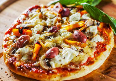 vejetaryen pizza Mozzarella peynir, zeytin, mantar, biber ve taze fesleğen. Ahşap masa arka plan üzerinde İtalyan pizza