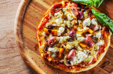vejetaryen pizza Mozzarella peynir, zeytin, mantar, biber ve taze fesleğen. Ahşap masa arka plan üzerinde İtalyan pizza