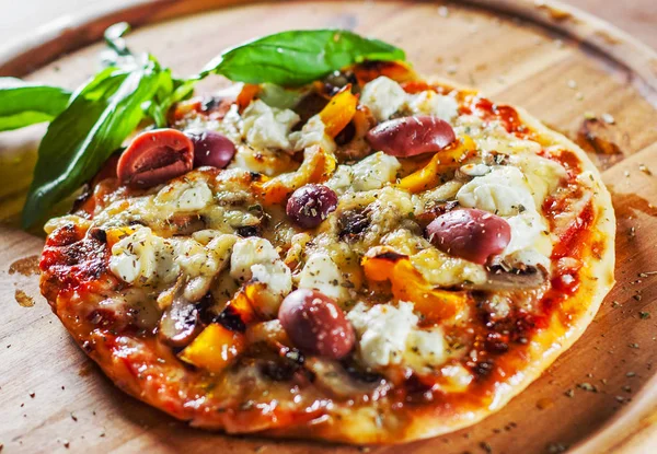 vegetarian pizza with Mozzarella cheese, olives, mushrooms, pepper and fresh basil. Italian pizza on wooden table background