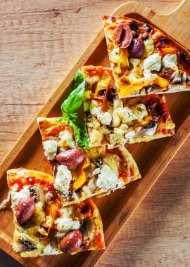 vejetaryen pizza Mozzarella peynir, zeytin, mantar, biber ve taze fesleğen dilimlenmiş. Ahşap masa arka plan üzerinde İtalyan pizza