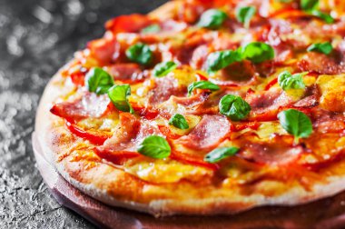 Pizza Mozzarella peyniri, jambon, biber, et, domates sosu, baharat ve taze fesleğen. Siyah arka plan üzerine İtalyan pizza