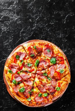 Pizza Mozzarella peyniri, jambon, biber, et, domates sosu, baharat ve taze fesleğen. Siyah arka plan üzerine İtalyan pizza