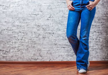 Kadın moda kavramı. Kot pantolon ve spor ayakkabı kopya alanı gri duvar zemin üzerine kadın bacaklar