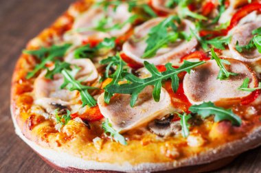 Pizza Mozzarella peyniri, mantar, jambon, domates sosu, biber, baharat ve taze roka. Ahşap masa arka plan üzerinde İtalyan pizza