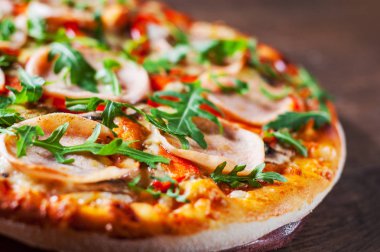 Pizza Mozzarella peyniri, mantar, jambon, domates sosu, biber, baharat ve taze roka. Ahşap masa arka plan üzerinde İtalyan pizza