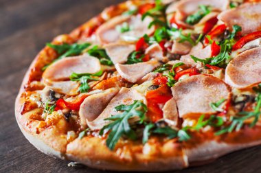 Pizza Mozzarella peyniri, mantar, jambon, domates sosu, biber, baharat ve taze roka. Ahşap masa arka plan üzerinde İtalyan pizza