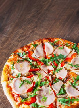 Pizza Mozzarella peyniri, mantar, jambon, domates sosu, biber, baharat ve taze roka. Ahşap masa arka plan üzerinde İtalyan pizza