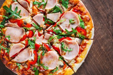Pizza Mozzarella peyniri, mantar, jambon, domates sosu, biber, baharat ve taze roka. Ahşap masa arka plan üzerinde İtalyan pizza