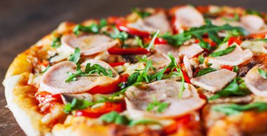 Pizza Mozzarella peyniri, mantar, jambon, domates sosu, biber, baharat ve taze roka. Ahşap masa arka plan üzerinde İtalyan pizza