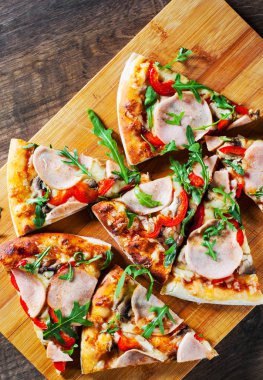 Pizza Mozzarella peyniri, mantar, jambon, domates sosu, biber, baharat ve taze roka. Ahşap masa arka plan üzerinde İtalyan pizza