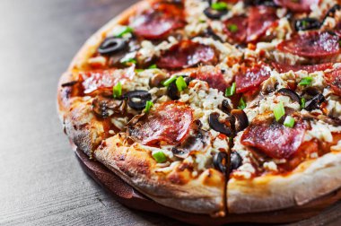 Mozzarella peyniri, salam, biber, biber, zeytin, baharat ve mantar pizza. Ahşap masa arka plan üzerinde İtalyan pizza