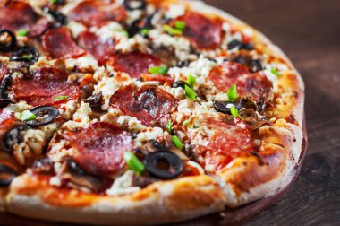 Mozzarella peyniri, salam, biber, biber, zeytin, baharat ve mantar pizza. Ahşap masa arka plan üzerinde İtalyan pizza