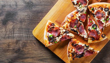 Mozzarella peyniri, salam, biber, biber, zeytin, baharat ve mantar pizza. Ahşap masa arka plan üzerinde İtalyan pizza