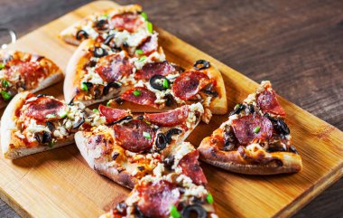 Mozzarella peyniri, salam, biber, biber, zeytin, baharat ve mantar pizza. Ahşap masa arka plan üzerinde İtalyan pizza